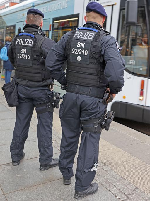 Zwei Polizisten stehen vor einer Straßenbahn in Dresden