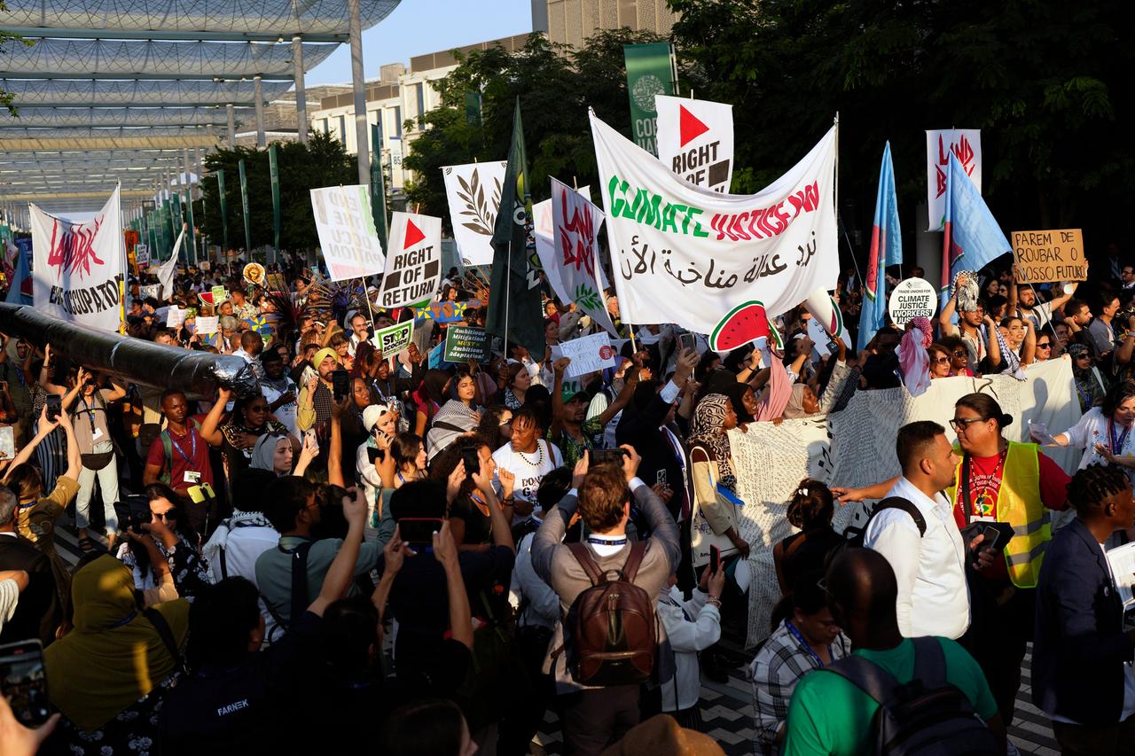 Eine Menschenmenge zieht durch Dubai, die Demonstranten halten Plakate in die Höhe.
