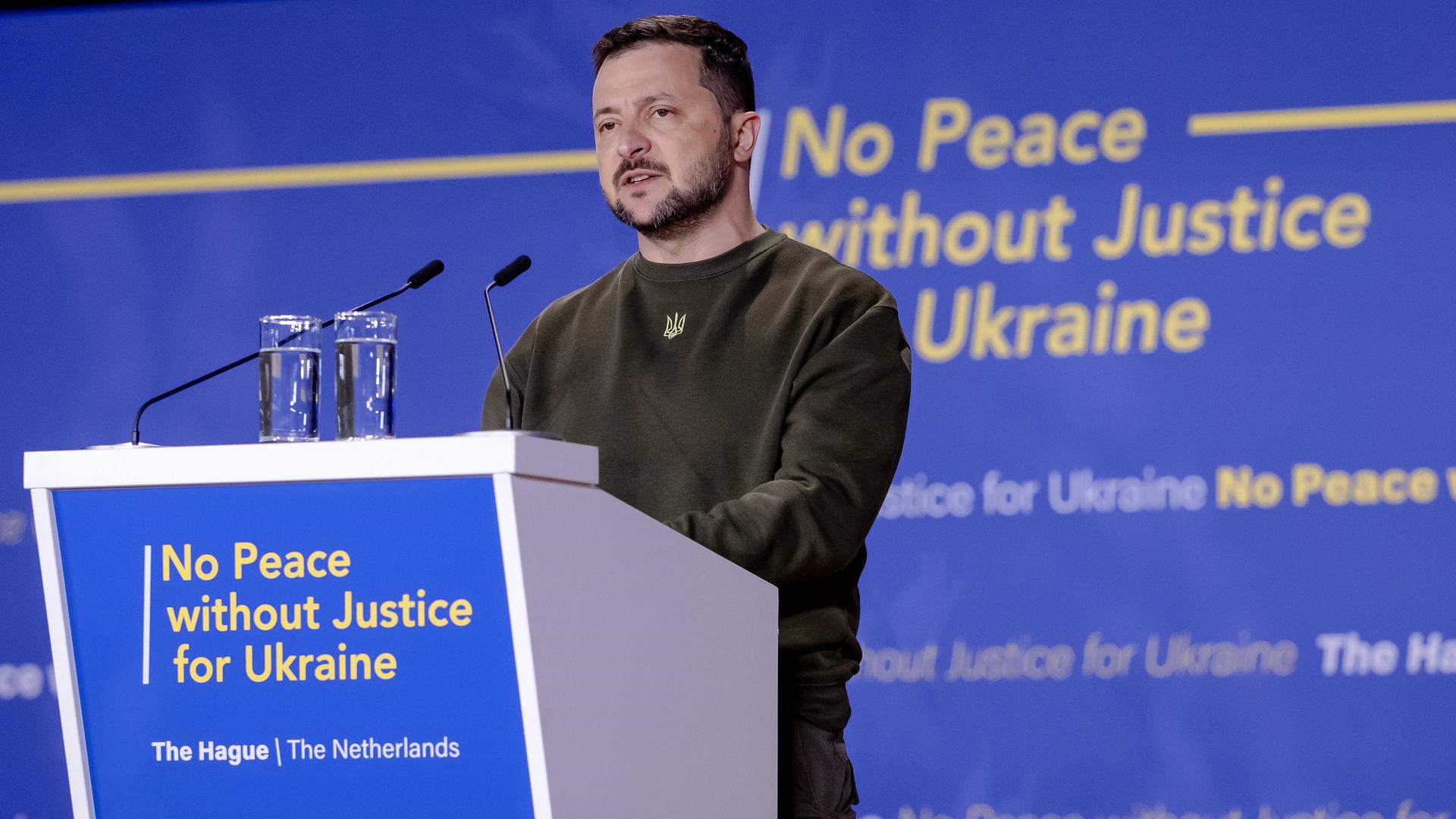 Der ukrainische Präsident Selenskyj steht bei seiner Rede auf dem Internationalen Strafgerichtshof in Den Haag hinter einem Rednerpult. Darauf steht: No Peace without Justice for Ukraine.