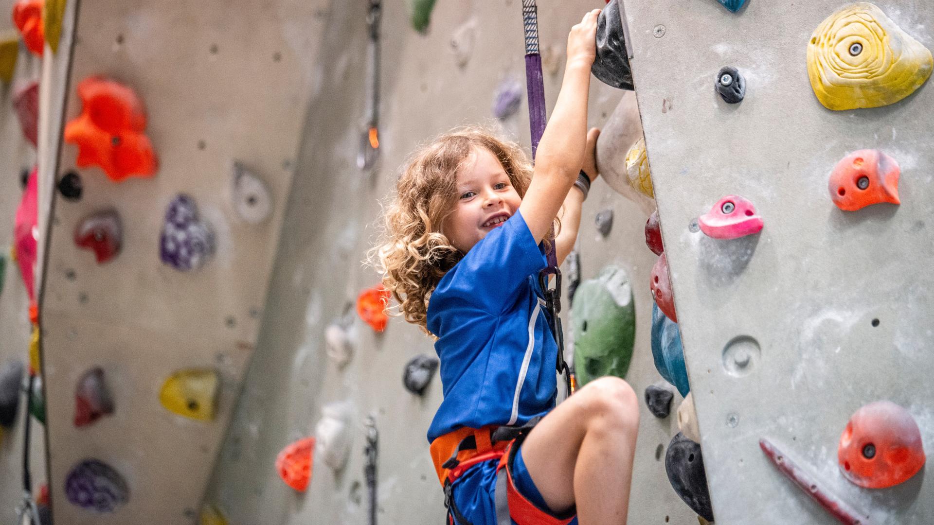 EIn Mädchen klettert in einer Kletterhalle