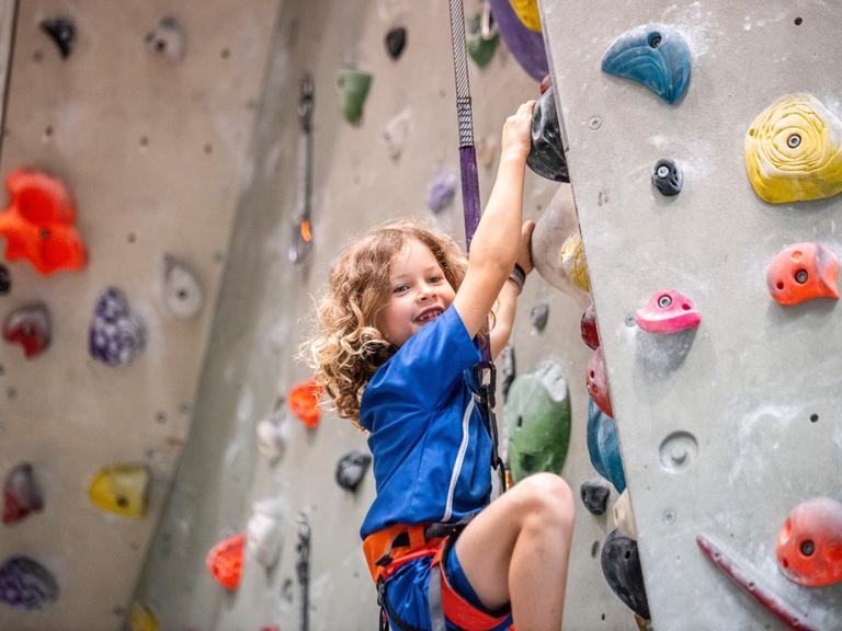EIn Mädchen klettert in einer Kletterhalle