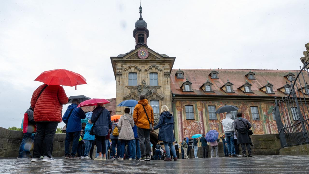 Tag des offenen Denkmals: Zahlreiche Menschen stehen mit Regenschirmen vor dem Alten Rathaus in Bamberg.