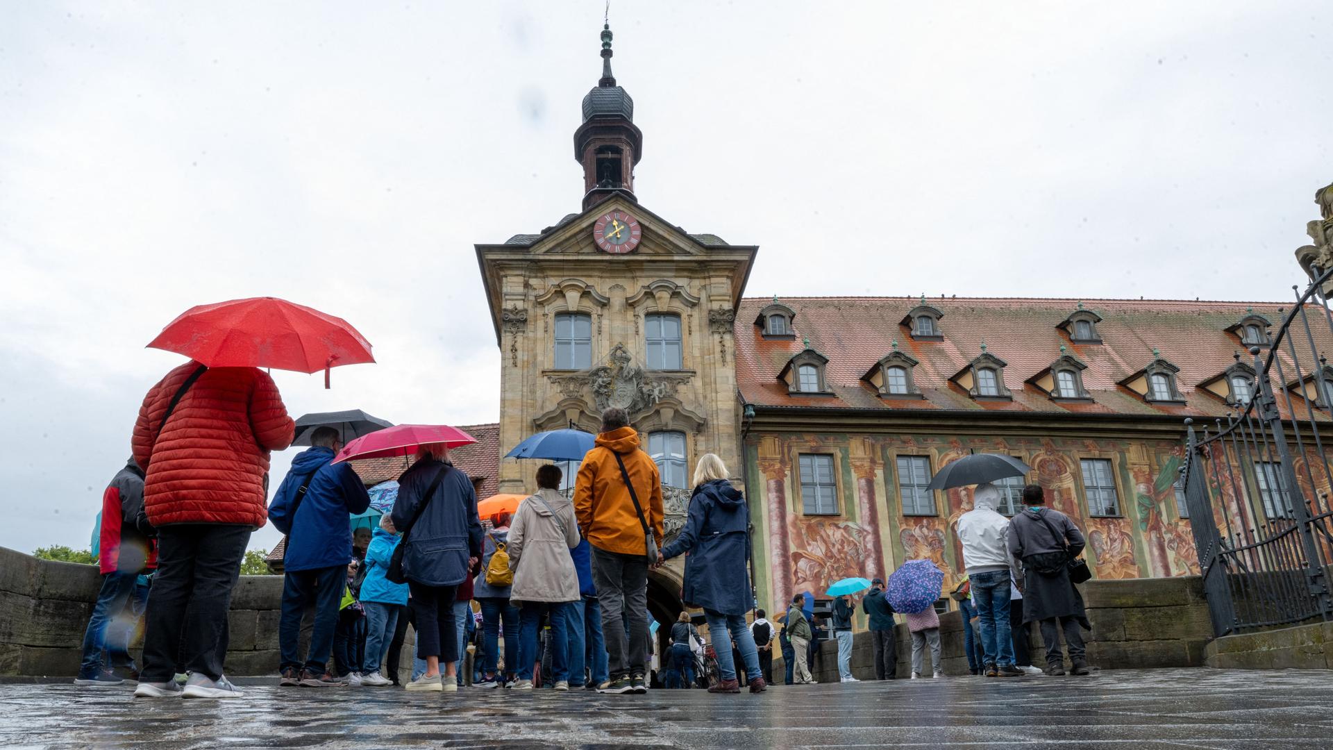 Tag des offenen Denkmals: Zahlreiche Menschen stehen mit Regenschirmen vor dem Alten Rathaus in Bamberg.