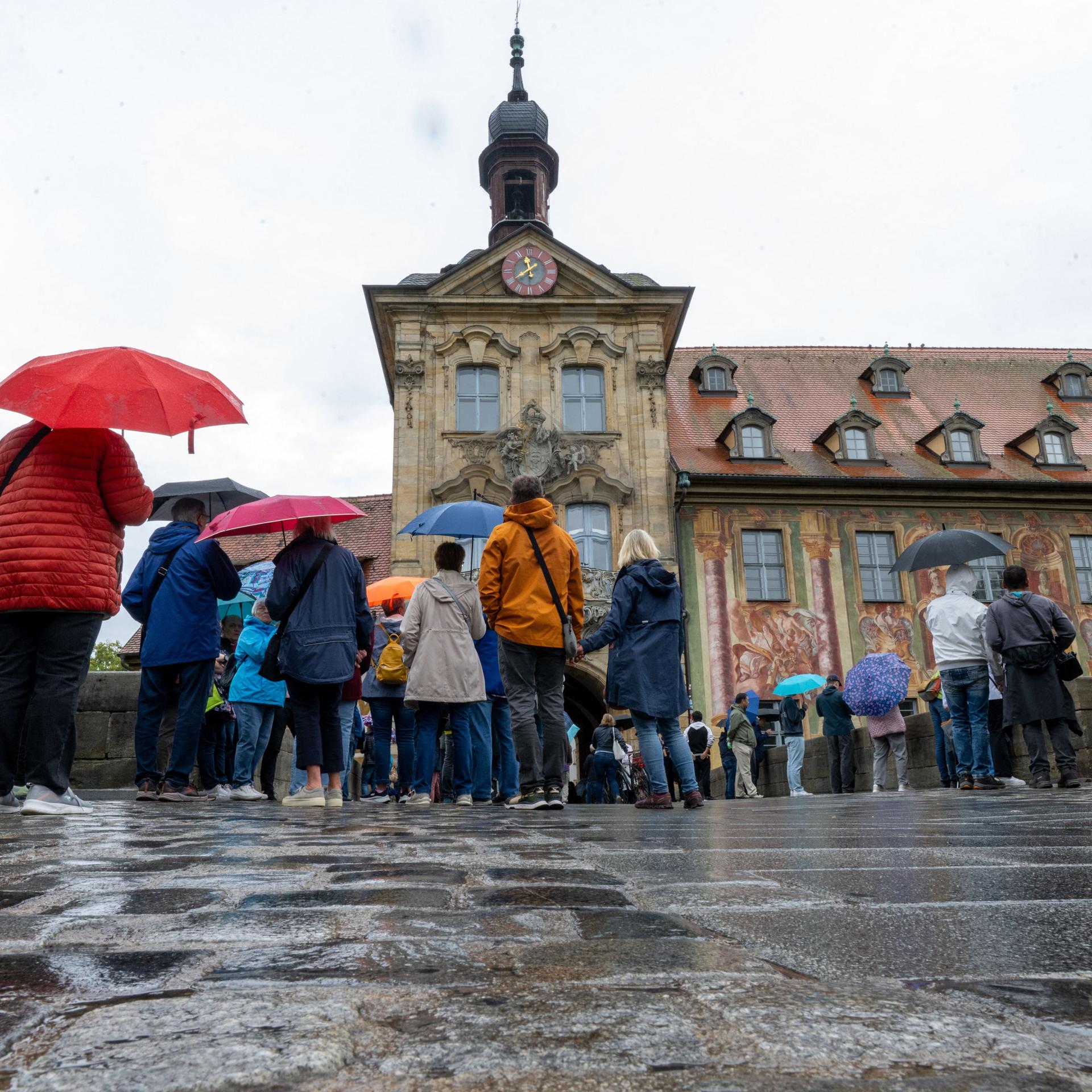 Tag des offenen Denkmals: Zahlreiche Menschen stehen mit Regenschirmen vor dem Alten Rathaus in Bamberg.