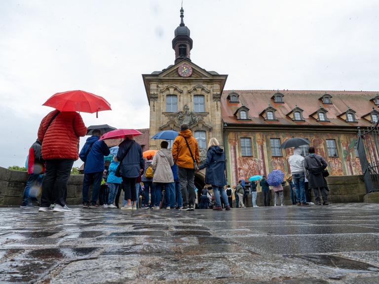 Tag des offenen Denkmals: Zahlreiche Menschen stehen mit Regenschirmen vor dem Alten Rathaus in Bamberg. Tag des offenen Denkmals: Zahlreiche Menschen stehen mit Regenschirmen vor dem Alten Rathaus in Bamberg.