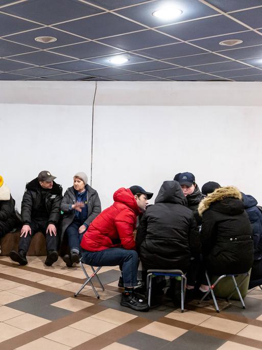 Nach einem Bombenalarm in Kiew suchen Menschen Schutz in einer Metro-Station. Menschen sitzen zusammen und unterhalten sich.