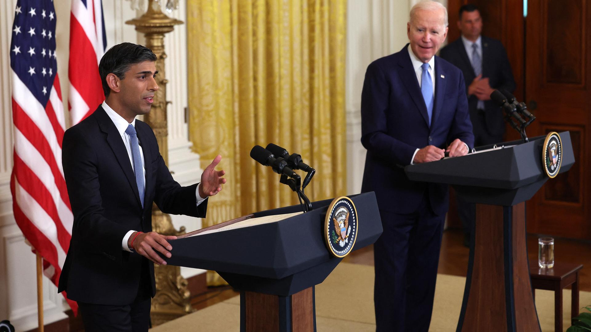 Der britische Premierminister Sunak und US-Präsident Biden stehen an Rednerpulten. Hinter ihnen sind die Flaggen ihrer Länder zu erkennen. Der britische Premierminister Sunak und US-Präsident Biden stehen an Rednerpulten. Hinter ihnen sind die Flaggen ihrer Länder zu erkennen.