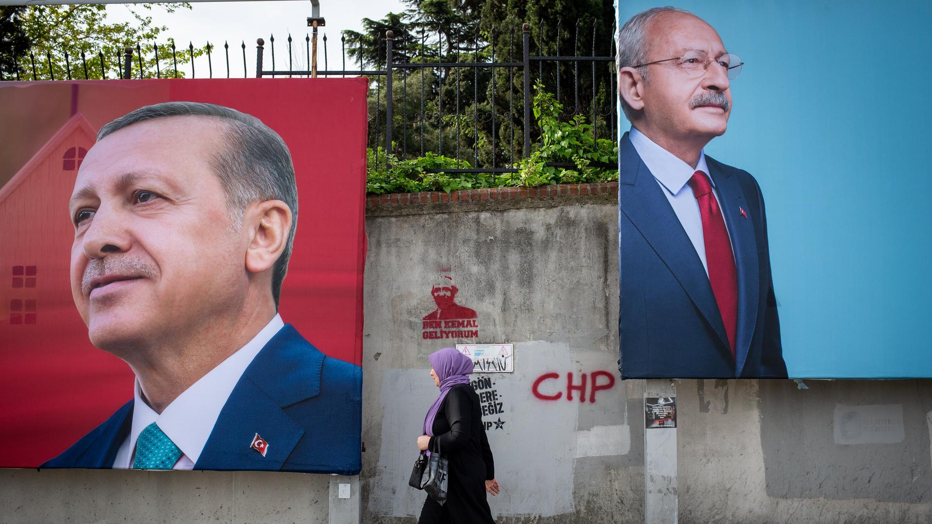 An einer Straße in Istanbul hängen große Werbeplakate von Langzeitpräsident Erdogan und Herausforderer Kemal Kilicdaroglu. Eine Frau geht an den Plakaten entlang.