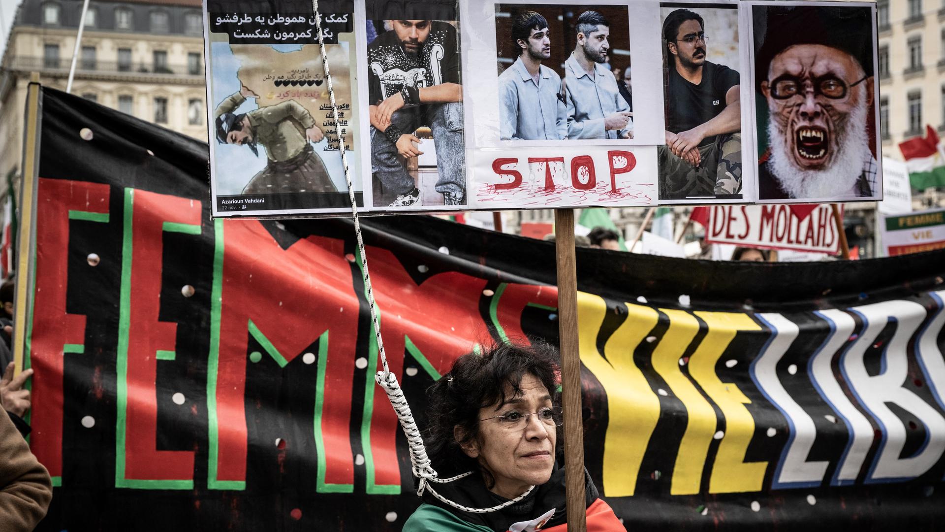 Demonstranten und Aktivisten in Teheran halten Plakate gegen die Hinrichtungen im Iran hoch. Im Vordergrund steht eine Frau, neben ihr baumelt ein Galgenstrick.