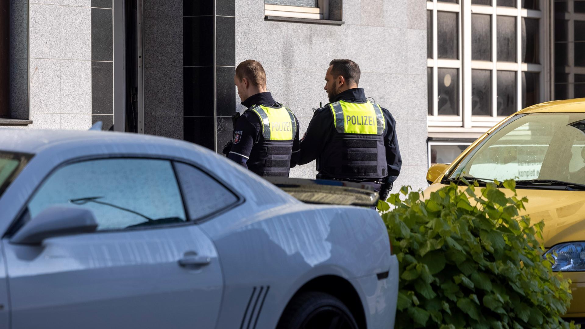 Zwei Polizeibeamte stehen vor dem Eingang eines Gebäudes.