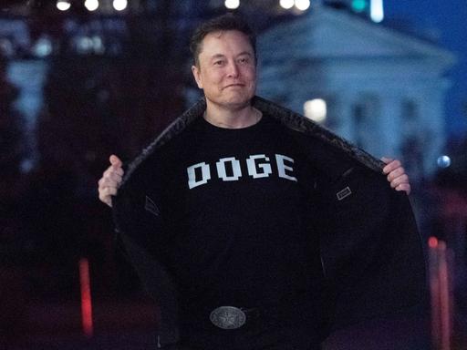 Elon Musk zeigt den Medien sein Oberteil mit der Aufschrift "DOGE", während er auf dem Südrasen des Weißen Hauses in Washington geht. 
