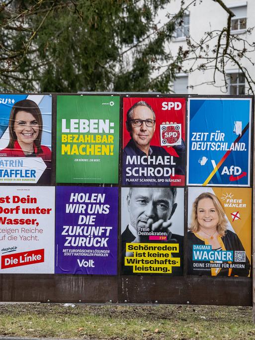 Eine Wand mit verschiedenen Wahlplakaten.