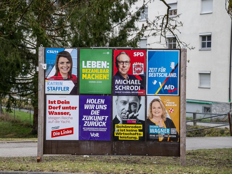 Eine Wand mit verschiedenen Wahlplakaten.