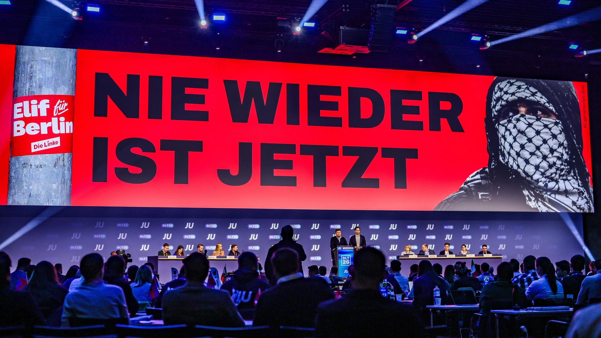 Deutschlandtag der Jungen Union: Auf dem LED-Screen ist Schriftzug "Nie wieder ist jetzt" zu sehen, außerdem eine vermummte Person und der Sticker "Elif für Berlin". Die JU kritisiert die mögliche Koalition von Linken, SPD und Grünen in Berlin. 