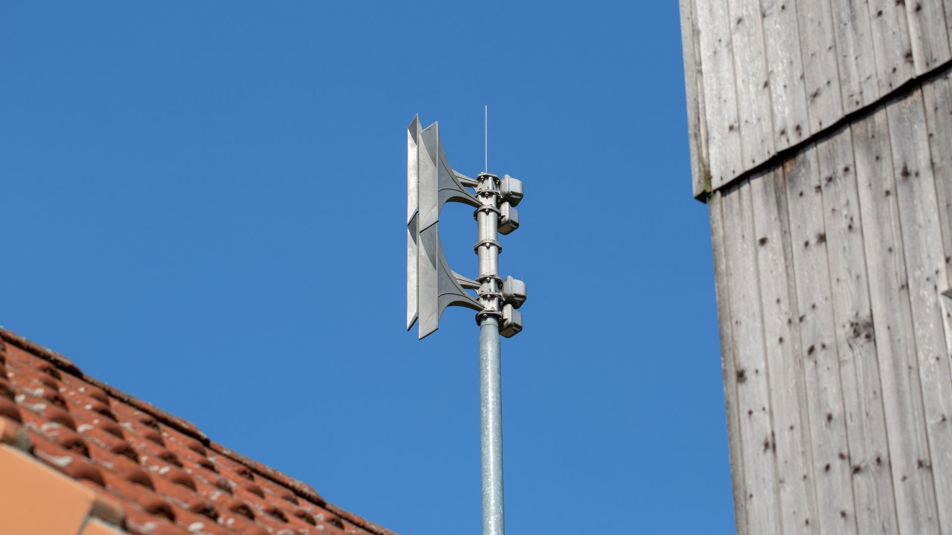 Auf einem Mast auf einem Dach ist eine Sirene montiert. 
