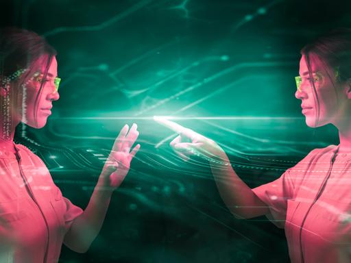Eine junge Frau mit Laborbrille steht ihrem digitalem Spiegelbild gegenüber, in einer grünlich schimmernden Beleuchtung, es scheibt, als programmiert sie etwas (Fotomontage)