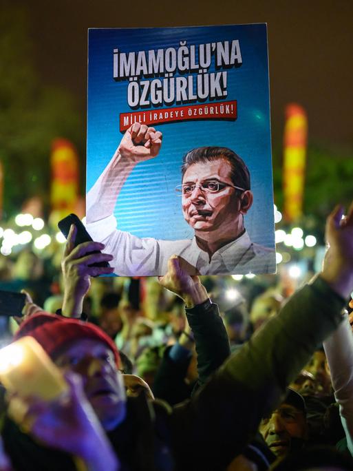 Demonstranten halten bei einem Protest ein Poster von Ekrem Imamoğlu in die Höhe.