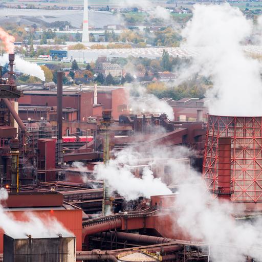Das Bild zeigt eine Industrieanlage, über der zahlreiche Dampfwolken aufsteigen.