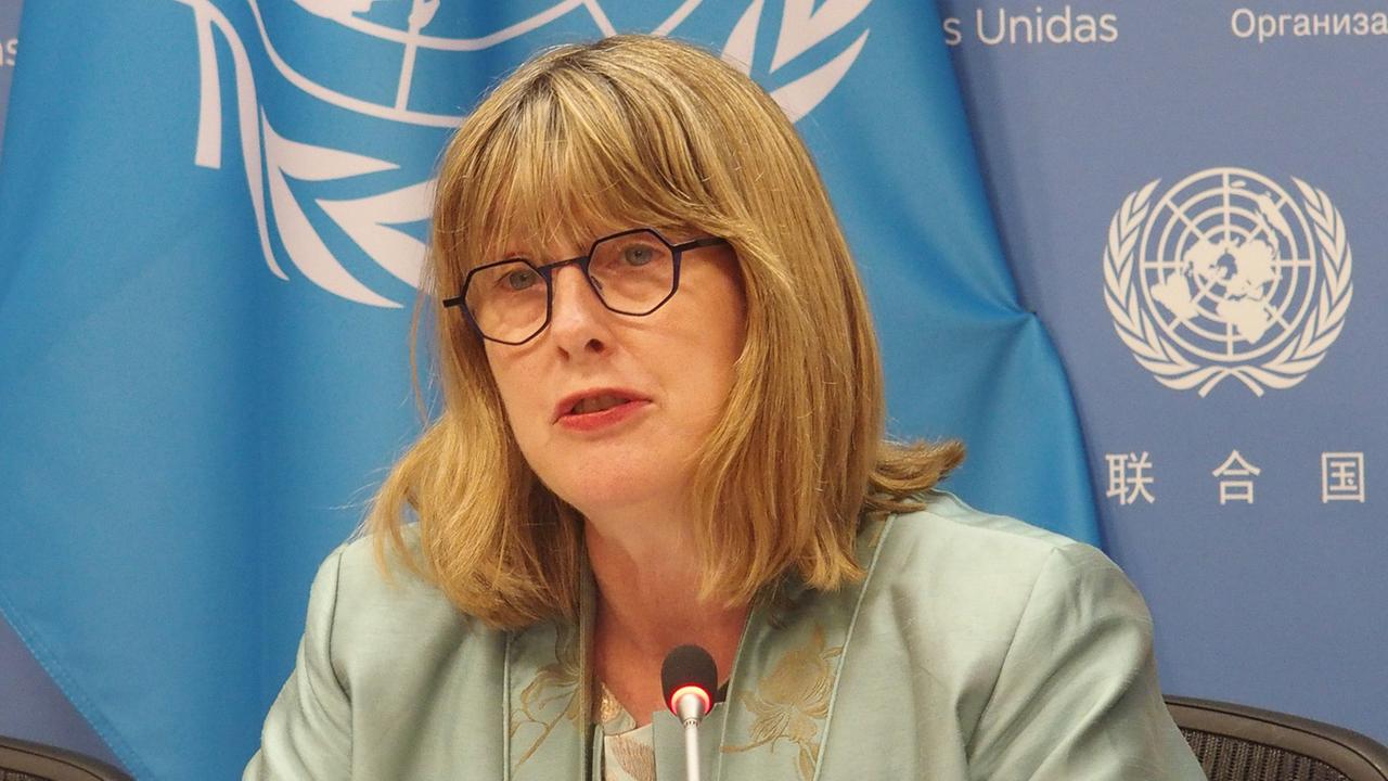 Die UNO-Expertin Ni Aolain spricht auf einer Pressekonferenz. Hinter ihr sieht man blaue Banner mit dem Logo der Vereinten Nationen.