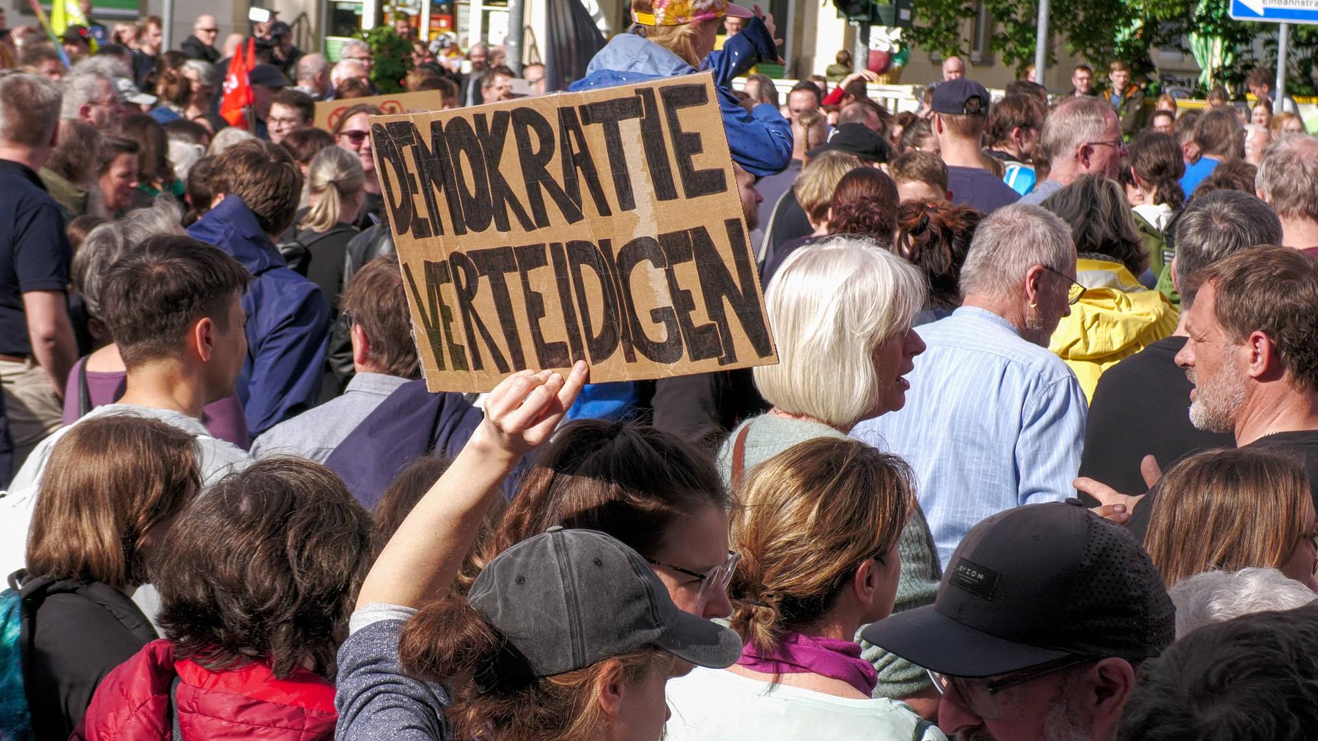 Nach dem Angriff auf den SPD-Politiker Ecke haben sich rund 2.000 Menschen zu einer Solidaritätskundgebung in Dresden versammelt. Teilnehmer halten Plakate mit der Aufschrift "Demokratie verteidigen" hoch. 