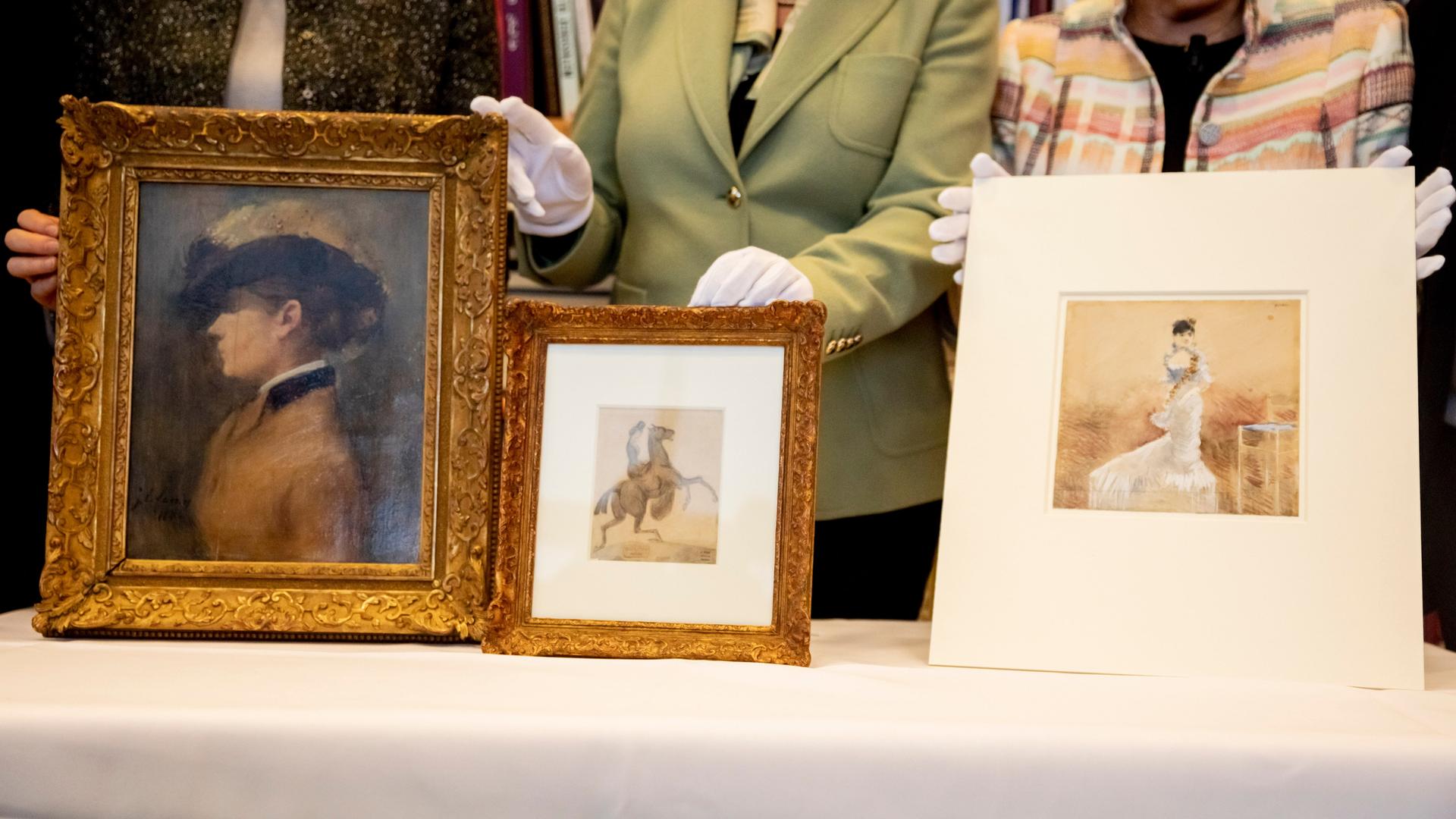 Drei als NS-Raubkunst identifizierte Kunstwerke: das Aquarell "Dame im Abendkleid" (r) und das Gemälde "Porträt einer Dame" (l) von Jean-Louis Forain, beide aus dem Bestand Cornelius Gurlitts, sowie die Zeichnung "Amazone mit aufbäumendem Pferd" (M) von Constantin Guys, welche zuletzt in Privatbesitz war.