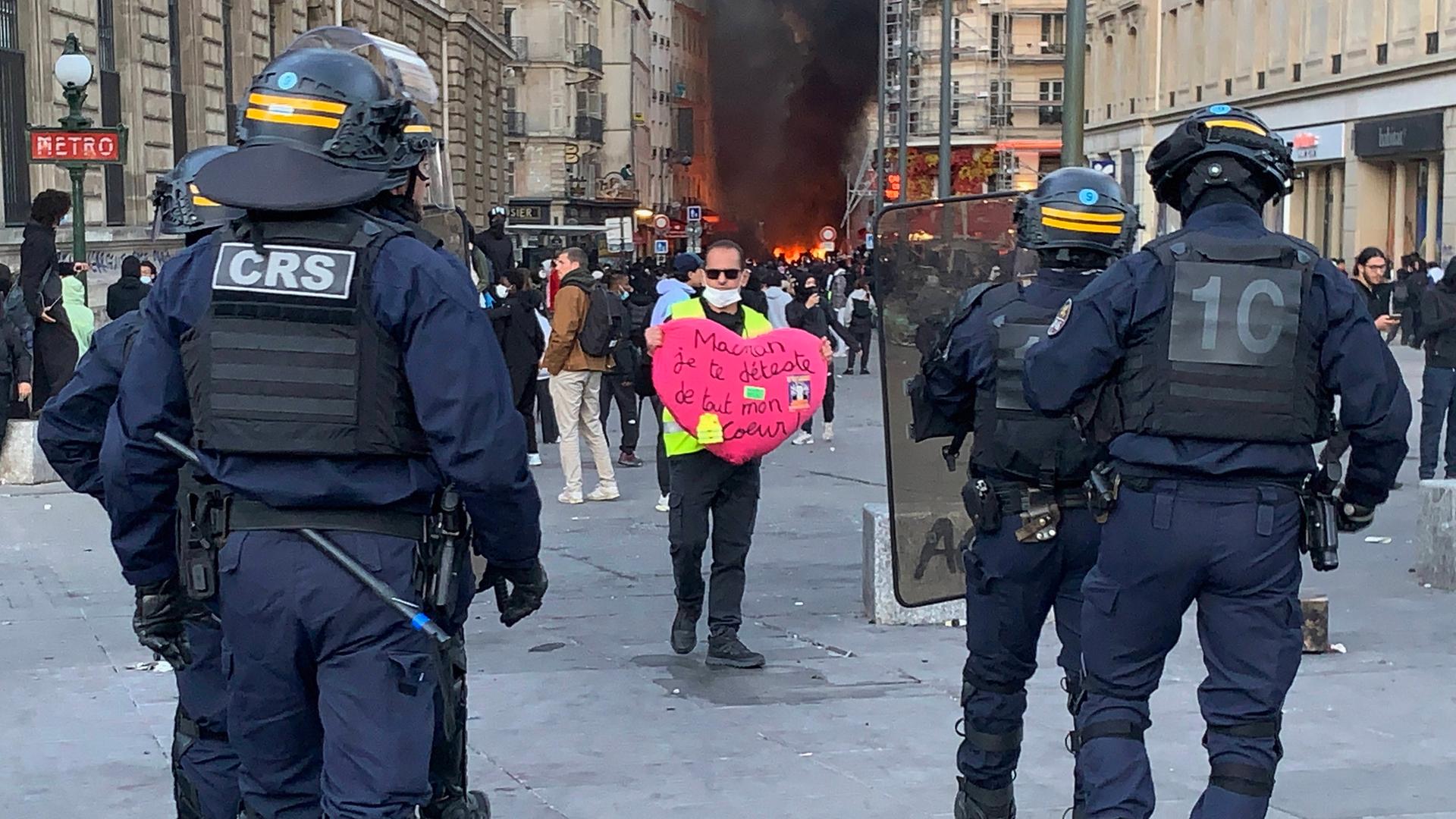 Ein Demonstrant hält vor einer Absperrung der Sicherheitskräfte auf dem Place de la République in Paris ein herzförmiges Plakat mit der Aufschrift „Macron, ich hasse dich von ganzem Herzen“ hoch Ein Demonstrant hält vor einer Absperrung der Sicherheitskräfte auf dem Place de la République in Paris ein herzförmiges Plakat mit der Aufschrift „Macron, ich hasse dich von ganzem Herzen“ hoch