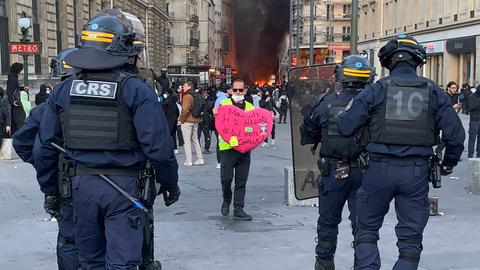 Ein Demonstrant hält vor einer Absperrung der Sicherheitskräfte auf dem Place de la République in Paris ein herzförmiges Plakat mit der Aufschrift „Macron, ich hasse dich von ganzem Herzen“ hoch