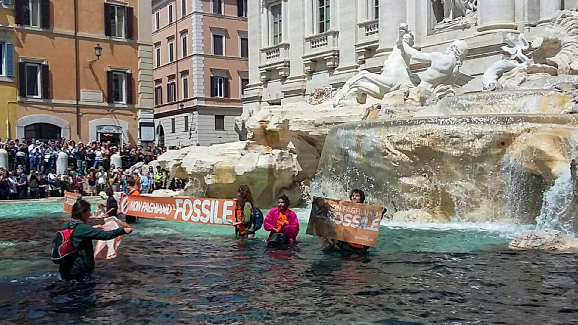 Aktivisten der Gruppe "Letzte Generation" stehen im Trevi-Brunnen, dessen Wasser sie schwarz gefärbt haben. Sie halten Banner hoch, auf denen unter anderem steht: "Non pagiame Fossile", also übersetzt etwa: "Wir wollen nicht für fossile Energien bezahlen".