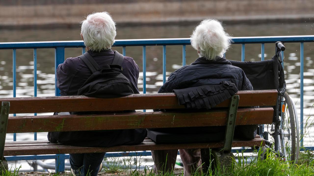Senioren sitzen auf einer Parkbank am Fluss.