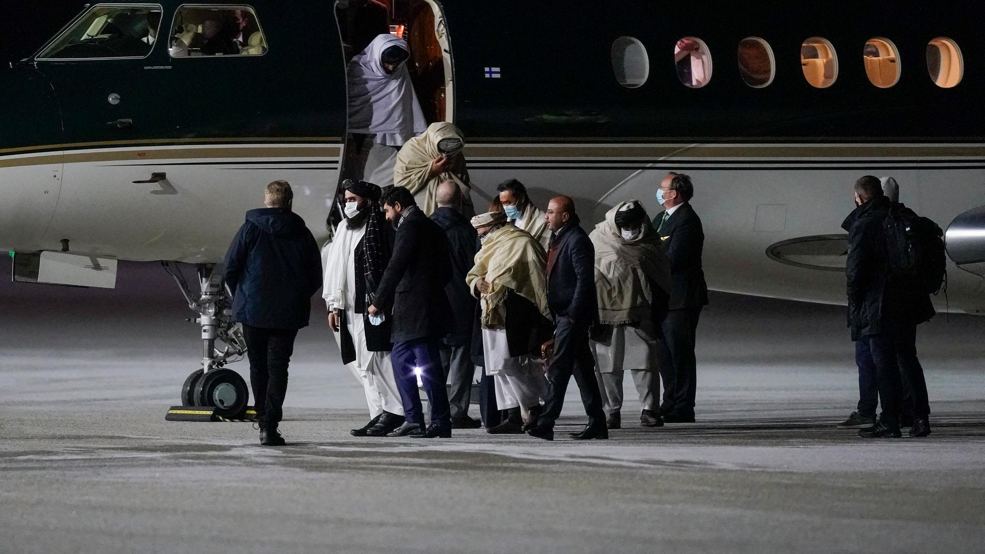 Vertreter der Taliban verlassen nach der Landung am Flughafen Oslo ein Flugzeug.