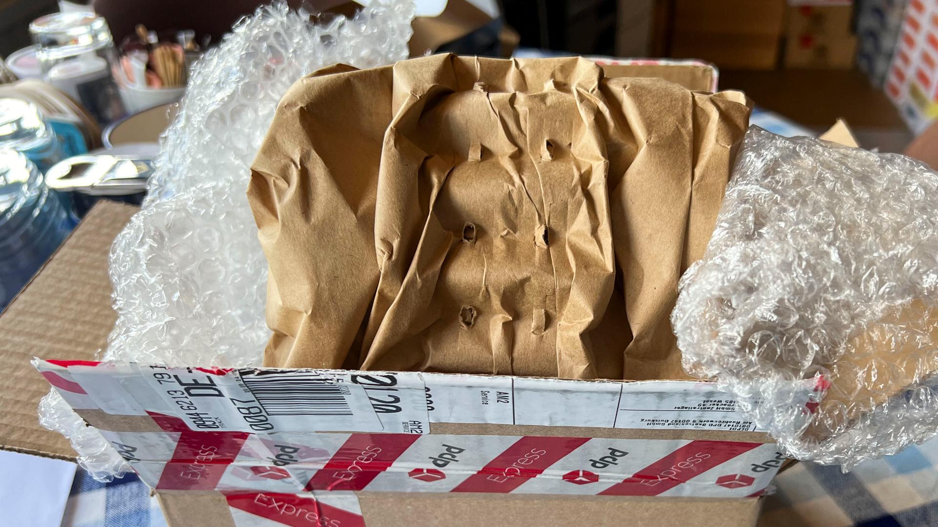 Ein ausgepackter Karton steht auf einem Tisch. Im Karton liegt Luftpolsterfolie.