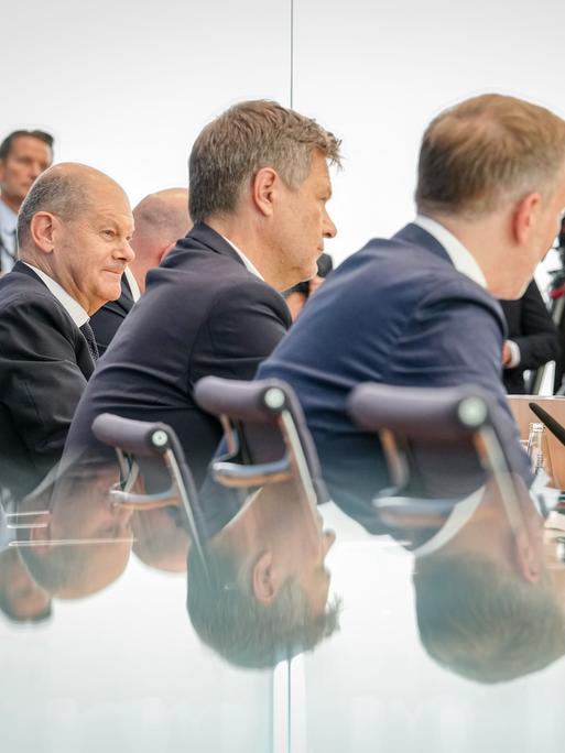 Bundeskanzler Olaf Scholz (SPD, l-r), Robert Habeck (Bündnis 90/Die Grünen), Bundesminister für Wirtschaft und Klimaschutz, und Christian Lindner (FDP), Bundesminister der Finanzen, sitzen bei einer Pressekonferenz zum Haushaltsplan 2025 nebeneinander. 