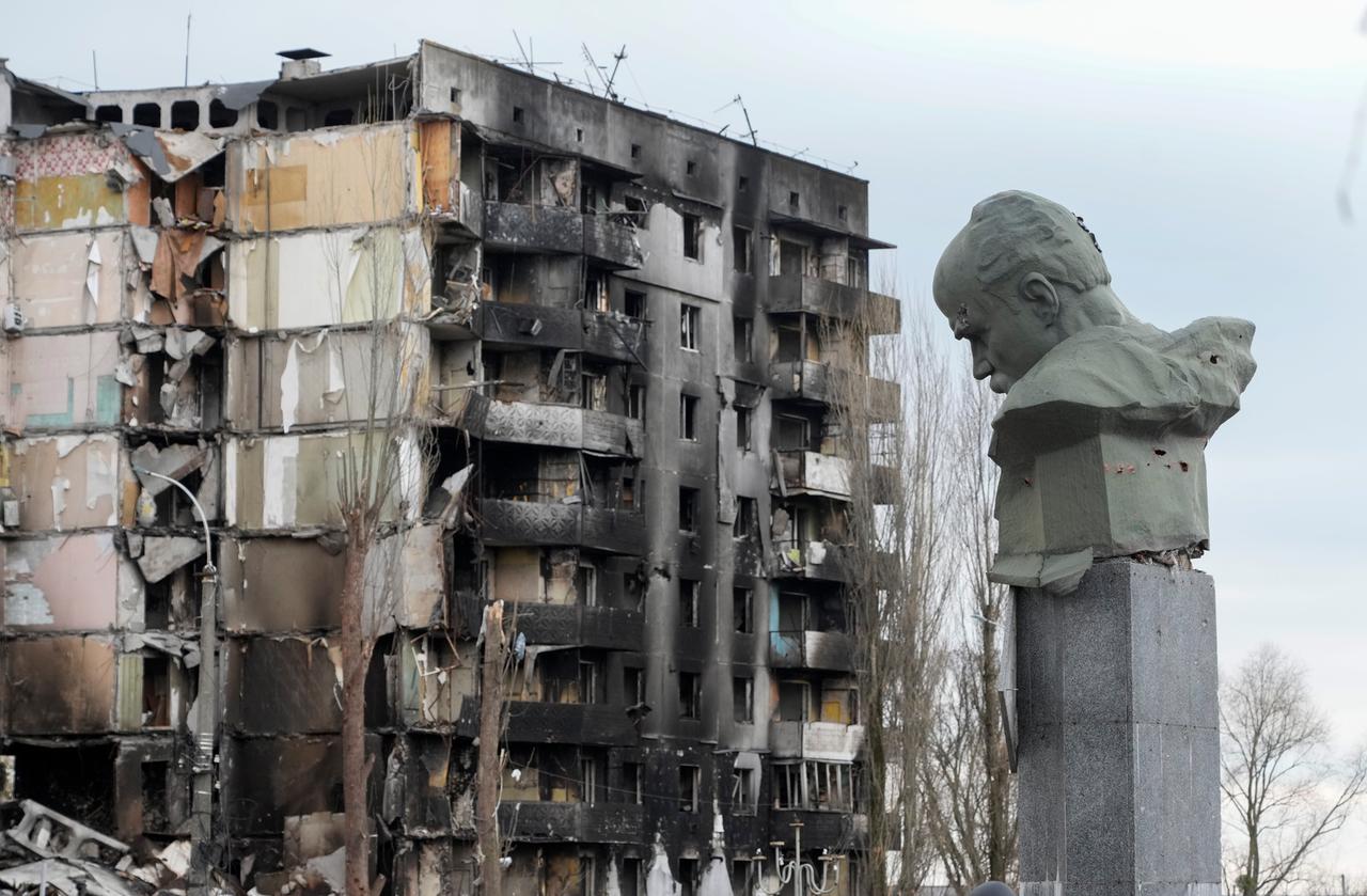 Das Taras-Schewtschenko-Denkmal, errichtet zu Ehren des ukrainischen Nationaldichters Taras Schewtschenko, steht beschädigt vor einem durch russischen Beschuss zerstörten Wohnhaus.
