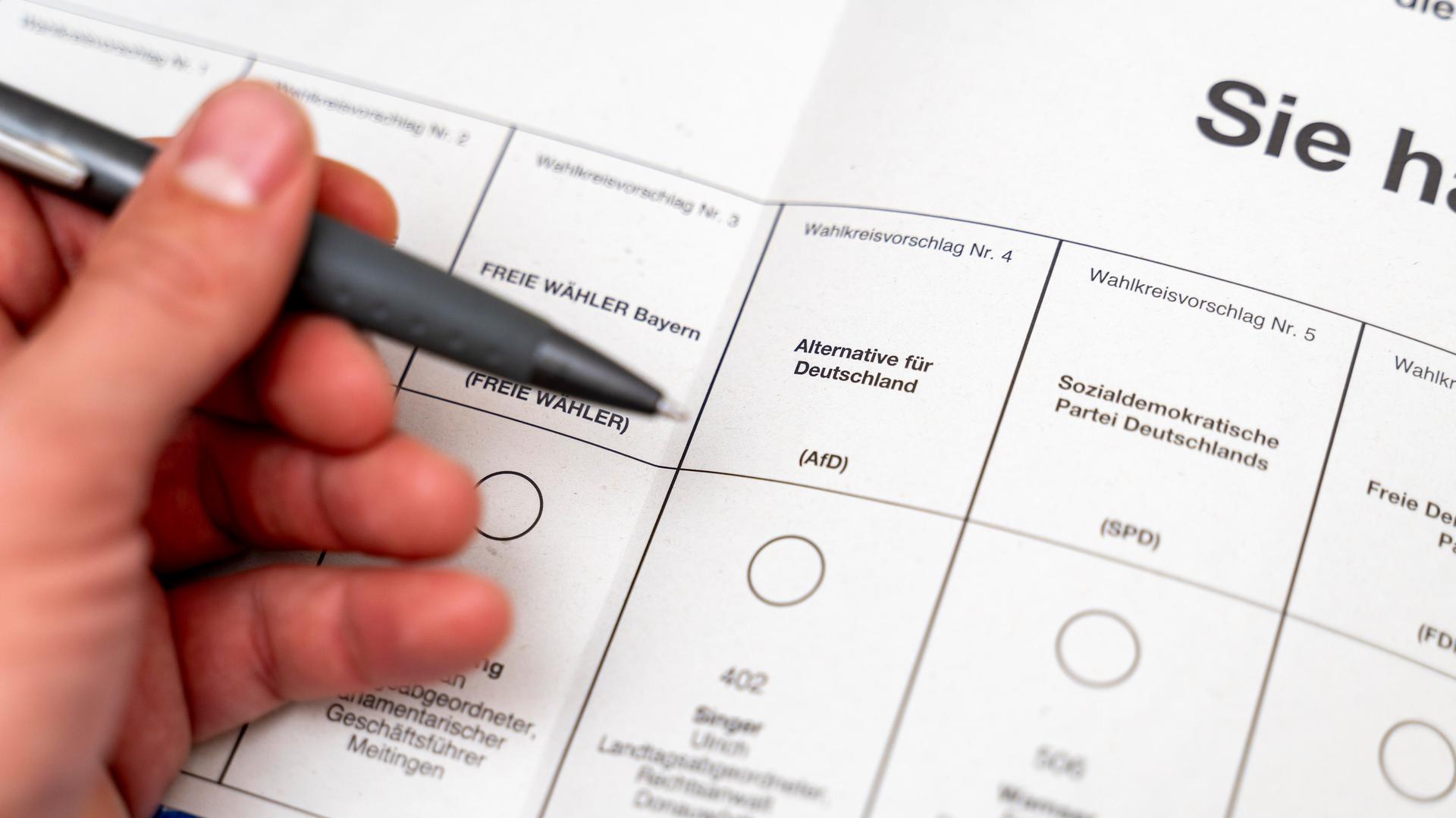 Stimmzettel bei der Briefwahl zur Landtagswahl am 8. Oktober in Bayern. Eine Hand hält einen Kugelschreiber vor dem Wahlfeld für die Partei AfD.