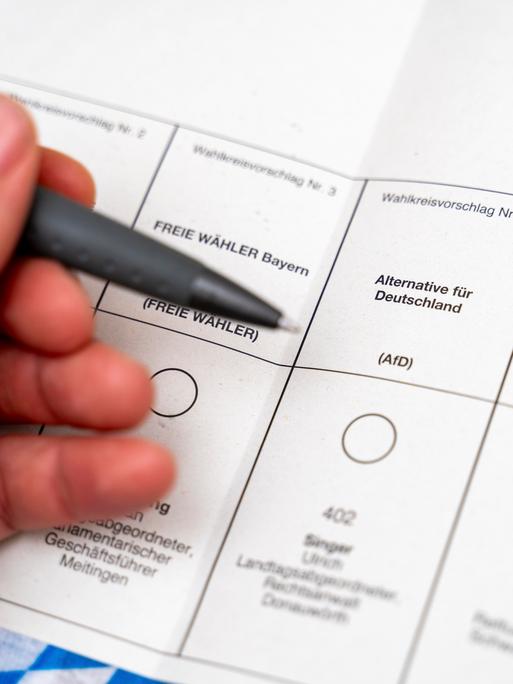 Stimmzettel bei der Briefwahl zur Landtagswahl am 8. Oktober in Bayern. Eine Hand hält einen Kugelschreiber vor dem Wahlfeld für die Partei AfD.