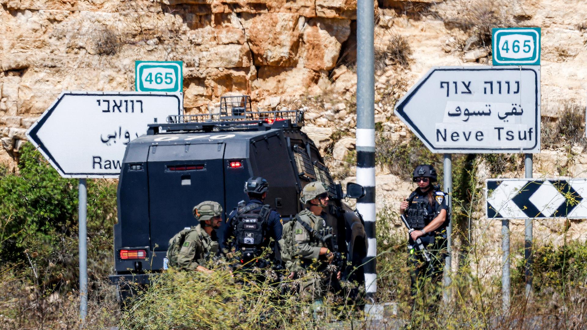 Bewaffnete Soldaten und Polizisten vor einem gepanzerten Einsatzfahrzeug