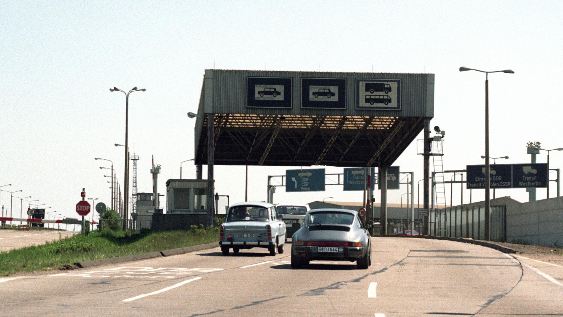 Ein Trabant und eine Porsche auf der A2, an der ehemaligen Grenzkontrollstelle Helmstedt-Marienborn. 