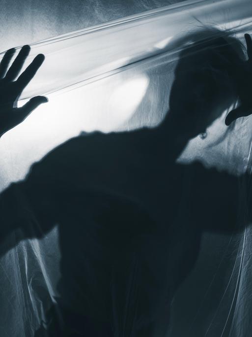 Schatten eines Jugendlichen vor weißgrauem Hintergrund