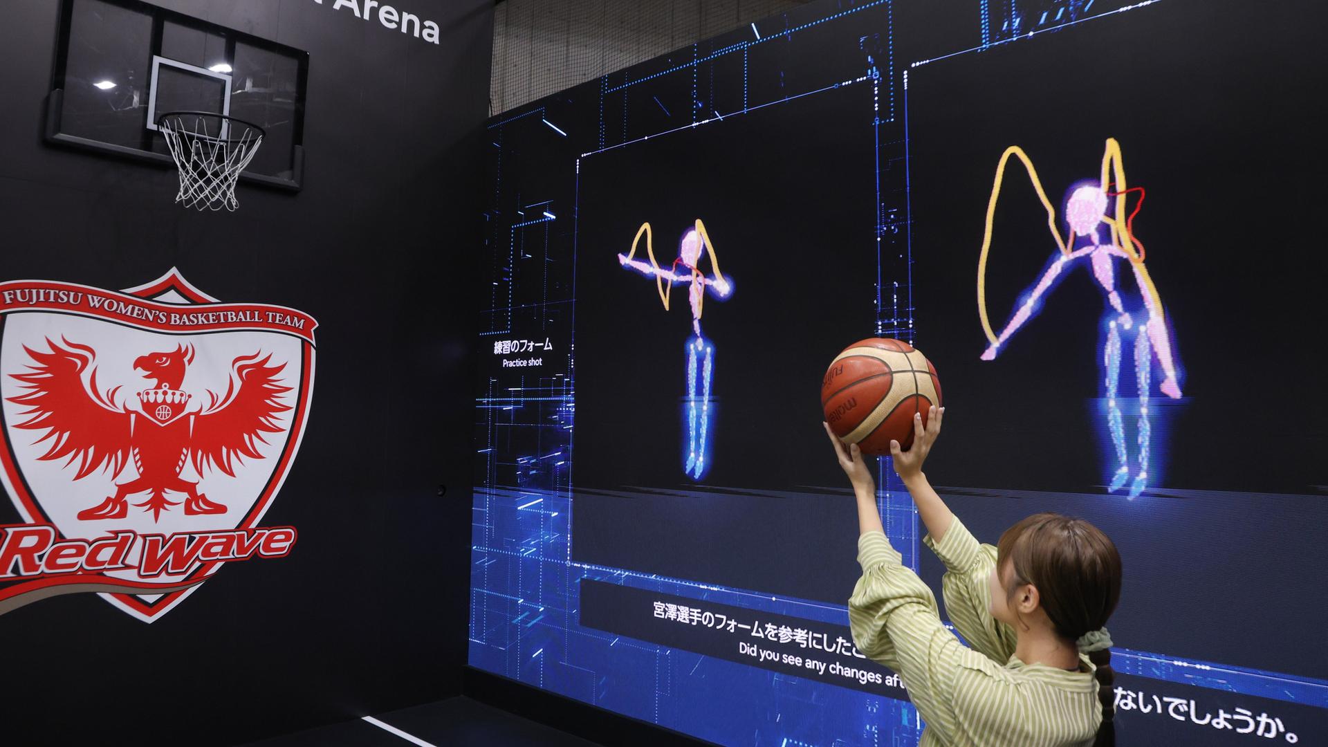 In Tokio stellte Fujitsu auf der Ceatec International im Oktober eine KI-Technologie vor, die beim Basketball Würfe analysiert und vergleicht. Zu sehen ist eine Frau, die vor Videoleinwänden auf einen Korb wirft.  