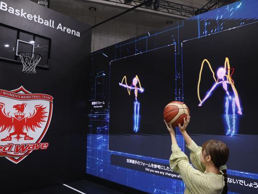 In Tokio stellte Fujitsu auf der Ceatec International im Oktober eine KI-Technologie vor, die beim Basketball Würfe analysiert und vergleicht. Zu sehen ist eine Frau, die vor Videoleinwänden auf einen Korb wirft.  