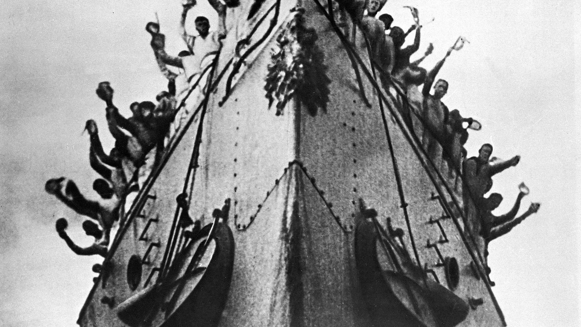 Ein Film-Bild aus "Panzerkreuzer Potemkin" von Sergei Eisenstein. Zu sehen ist ein großes Schiff mit Menschen an Deck.