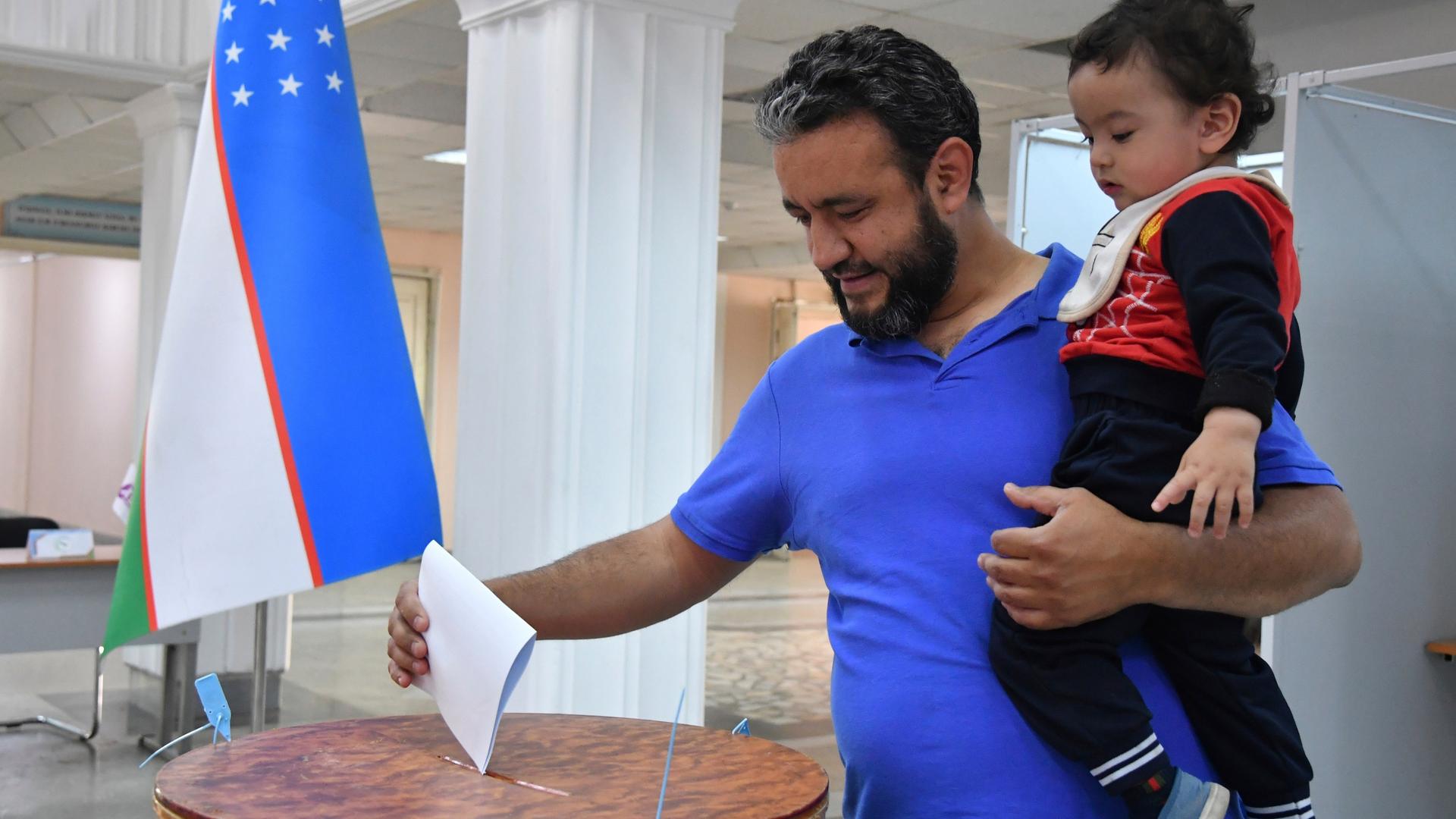 Ein Mann in Usbekistan hält sein Kind, während er in einem Wahllokal beim Verfassungsreferendum seine Stimme abgibt. Foto: Uncredited/AP/dpa +++ dpa-Bildfunk +++