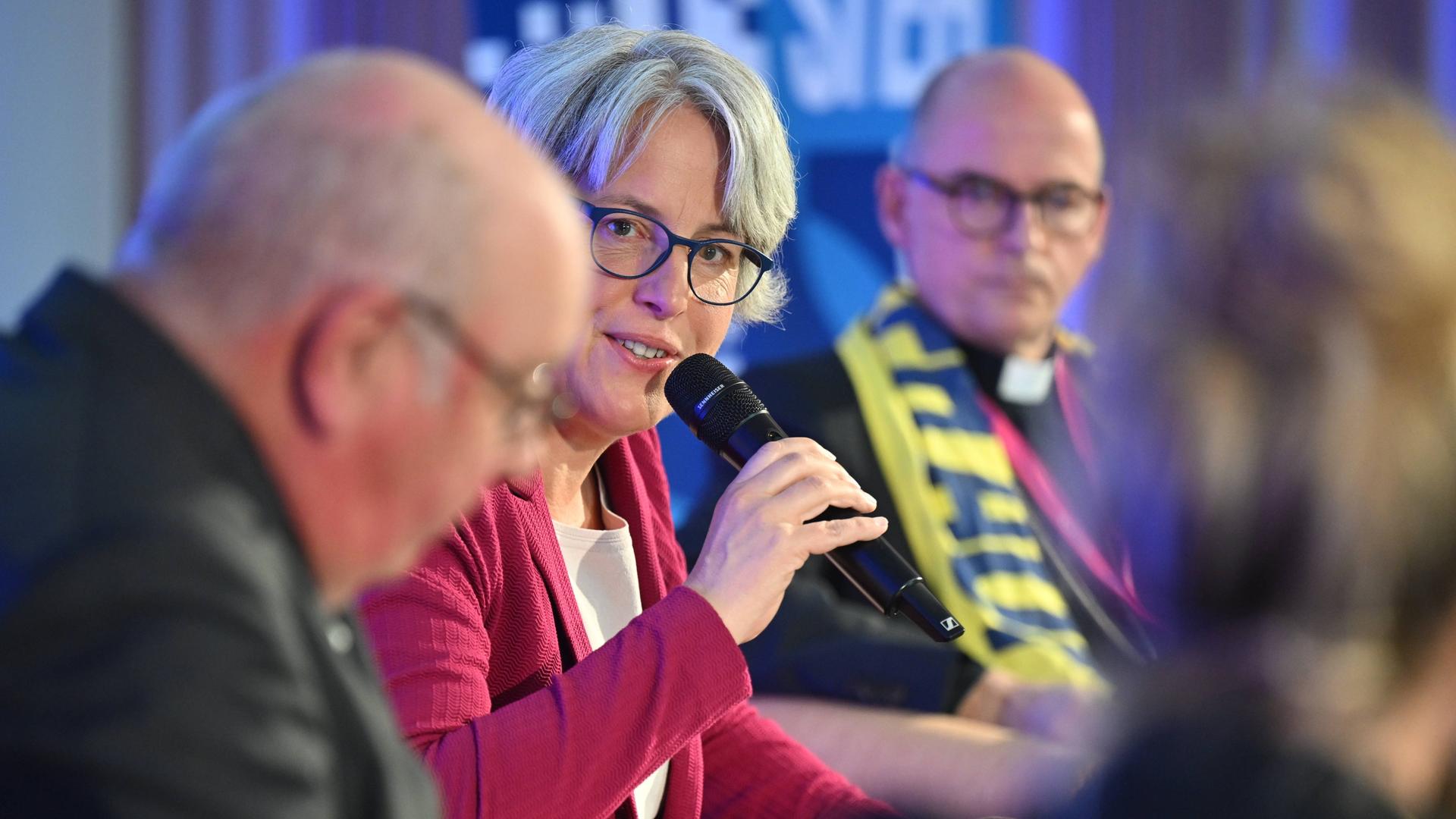 Eine Gesprächszene während der Podiumsdiskussion "Kann der Täter Richter sein" auf dem Katholikentag in Würzburg zeigt die Missbrauchsbeauftragte Kerstin Claus mit Mikrofon in der Hand, links von ihr sitzt Manfred Schmitz, rechts Bischof Franz Jung.