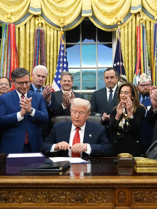 Präsident Donald Trump unterzeichnet im Oval Office des Weißen Hauses in Washington das Gesetz zur Wiederaufnahme der Regierungsgeschäfte. Er wird dabei umringt von Personen. Präsident Donald Trump unterzeichnet im Oval Office des Weißen Hauses in Washington das Gesetz zur Wiederaufnahme der Regierungsgeschäfte. Er wird dabei umringt von Personen.