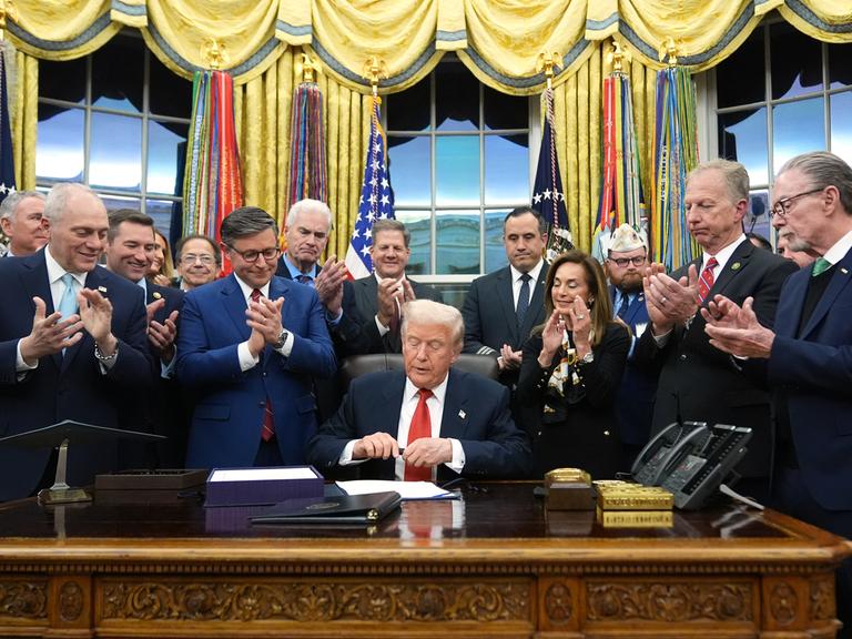 Präsident Donald Trump unterzeichnet im Oval Office des Weißen Hauses in Washington das Gesetz zur Wiederaufnahme der Regierungsgeschäfte. Er wird dabei umringt von Personen. Präsident Donald Trump unterzeichnet im Oval Office des Weißen Hauses in Washington das Gesetz zur Wiederaufnahme der Regierungsgeschäfte. Er wird dabei umringt von Personen.