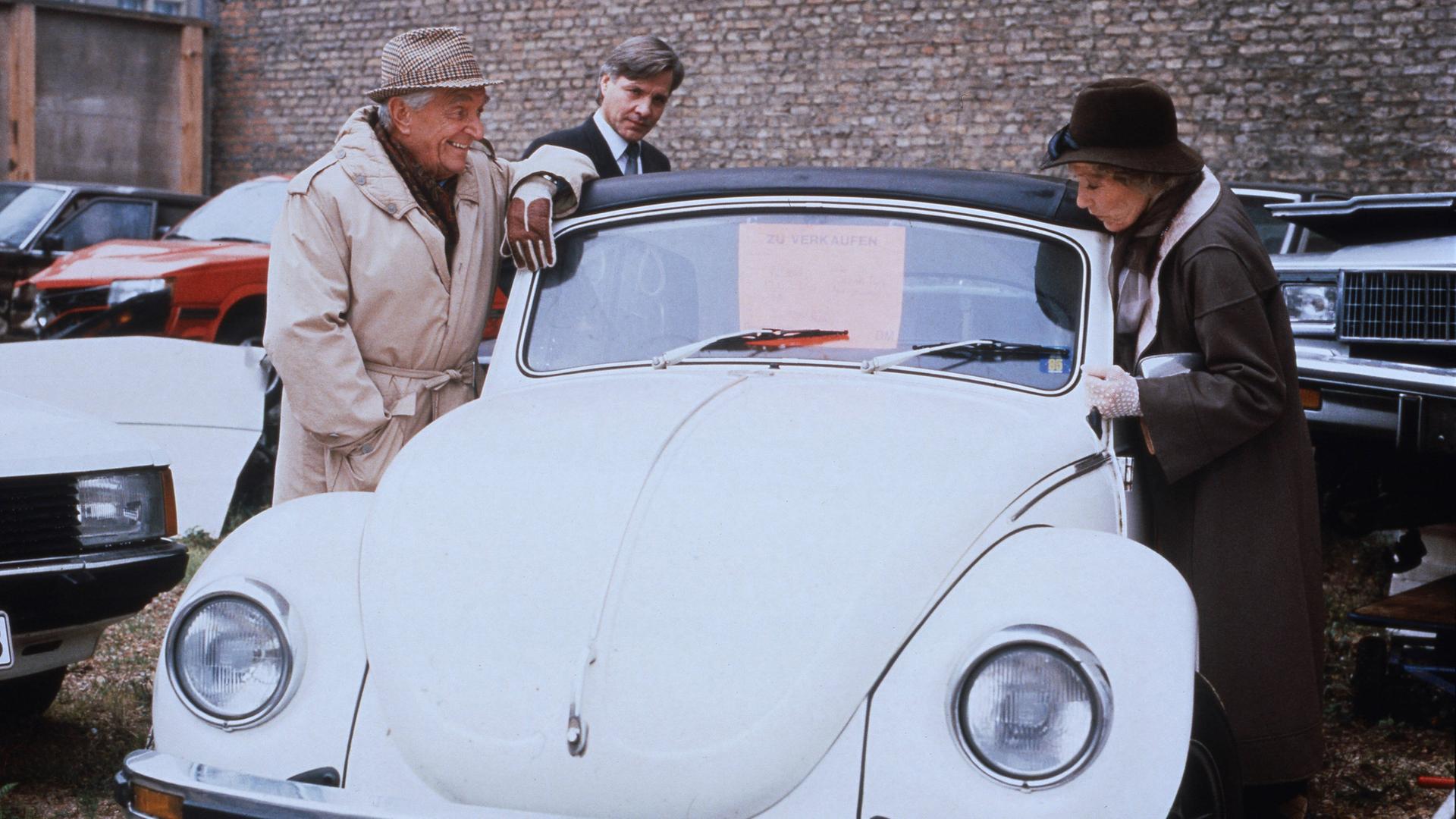 Ein Ehepaar bei einem VW-Käfer Einkauf, sie begutachten das Auto. Szene aus "Jakob und Adele", deutsche Fernsehserie 1981 - 1989.