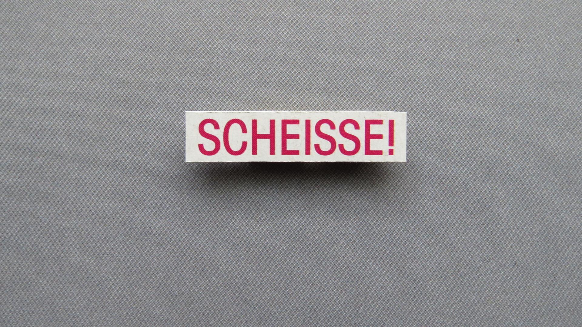 Auf einem kleinen Schild steht in roter Schrift "Scheisse!" Auf einem kleinen Schild steht in roter Schrift "Scheisse!"