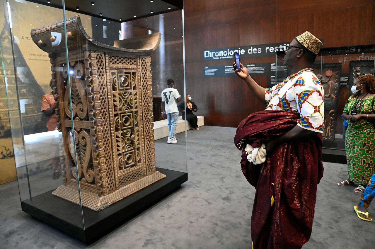 Ein Besucher fotografiert per Handy den ausgestellten Thron eines Königs des Reiches Dahomey.