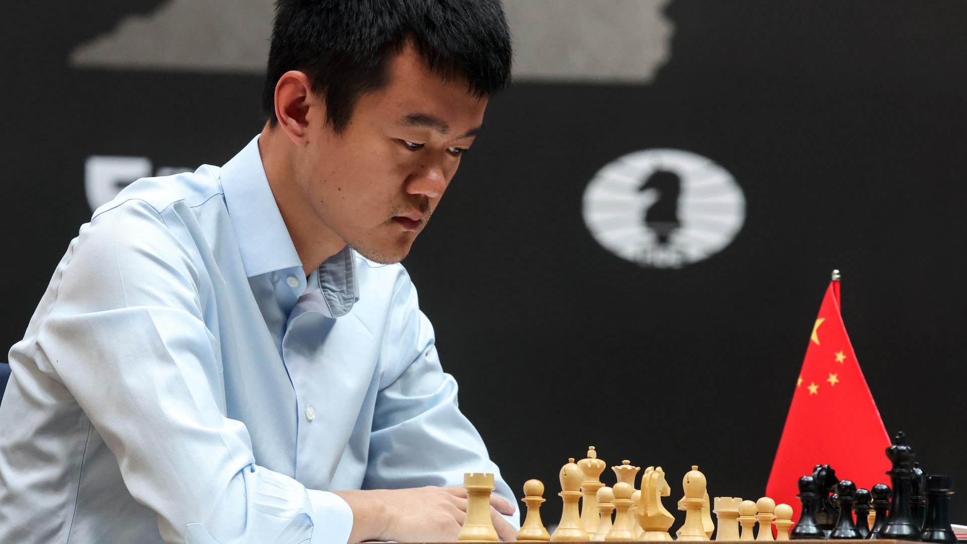 Ding Liren sitzt am Schachbrett und schaut konzentriert auf die Figuren Ding Liren sitzt am Schachbrett und schaut konzentriert auf die Figuren