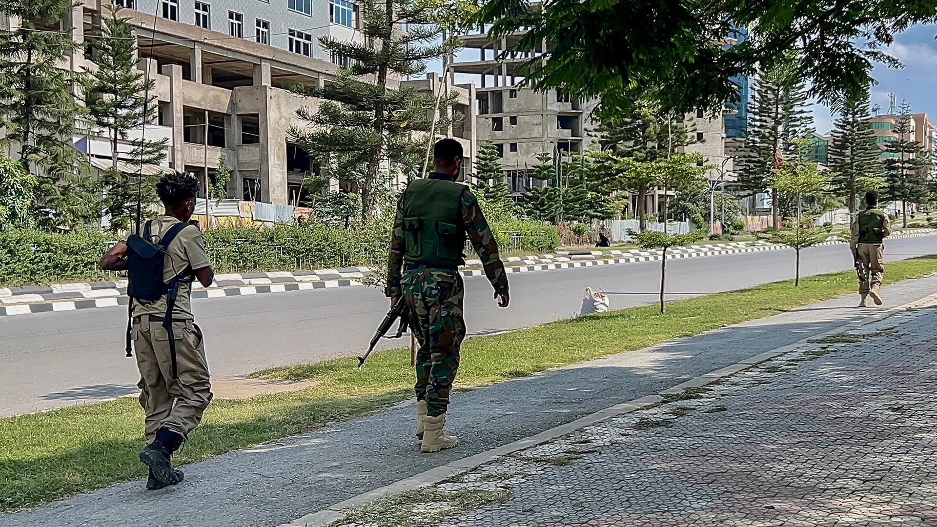 Auf einer Straße sind mehrere Personen in militärischer Kleidung und mit Waffen zu sehen. Auf einer Straße sind mehrere Personen in militärischer Kleidung und mit Waffen zu sehen.